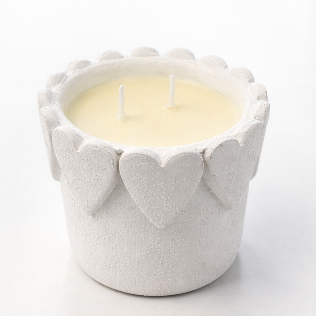 Candle in a textured white holder with heart designs on a white background